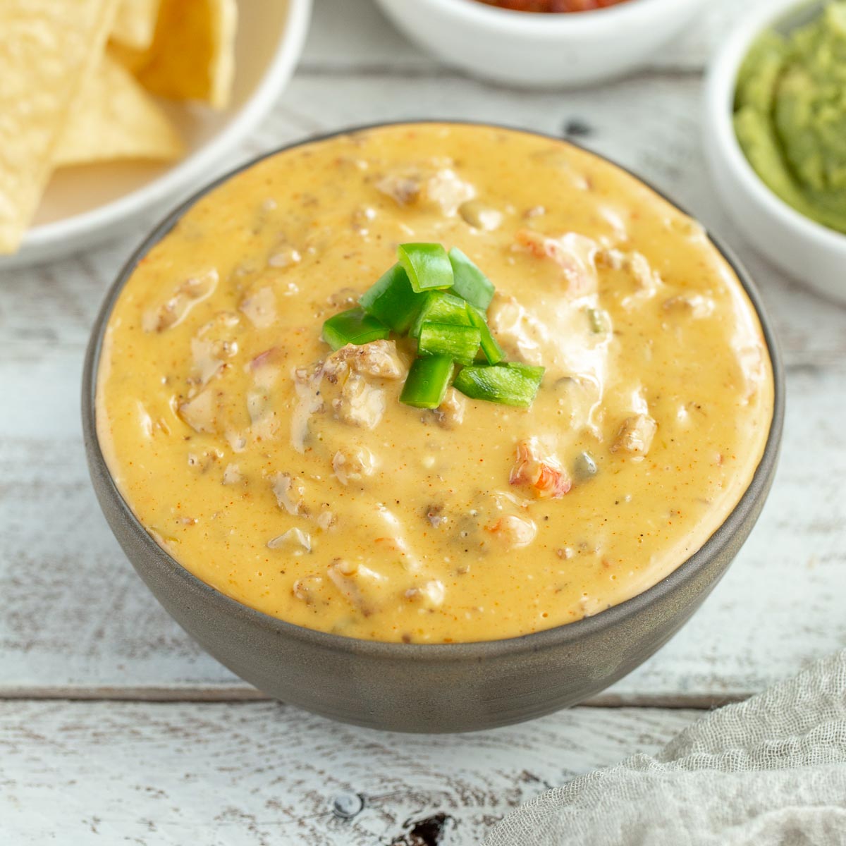 A bowl filled with smoked velveeta queso topped with chopped jalapeños.