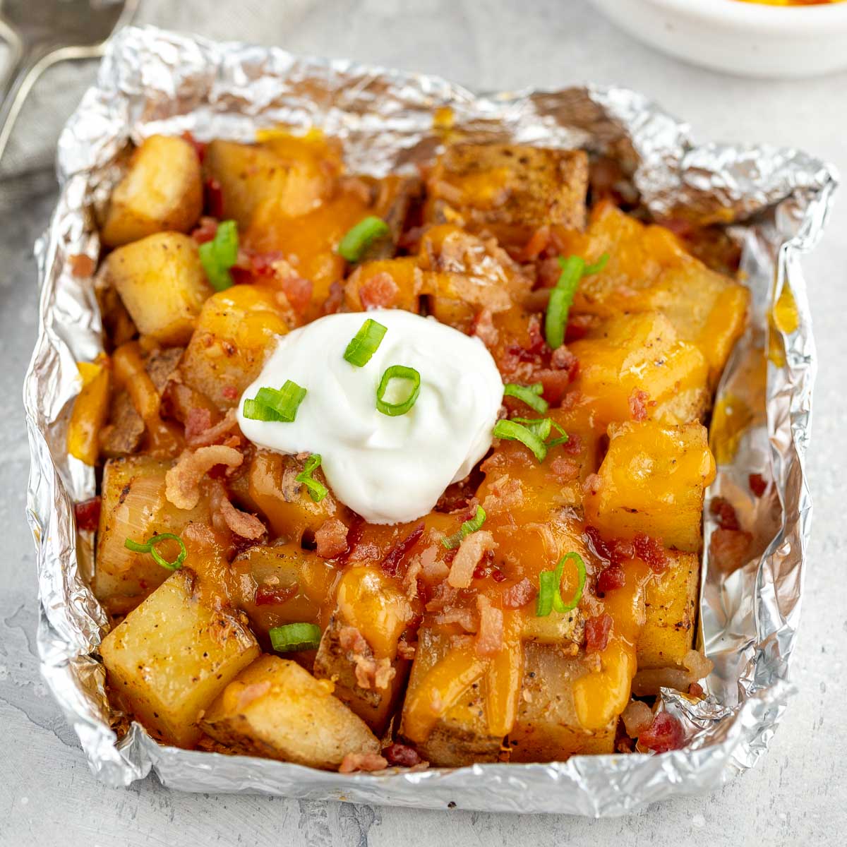 Potatoes in foil toped with cheese, bacon, and sour cream.