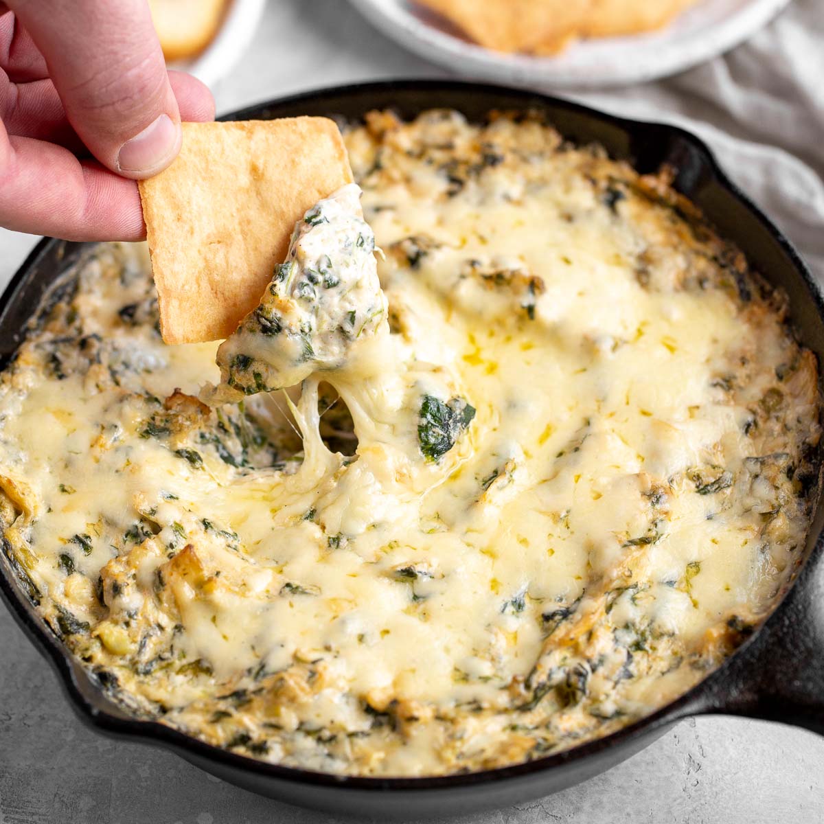 A cast iron skillet filled with smoked spinach artichoke dip.