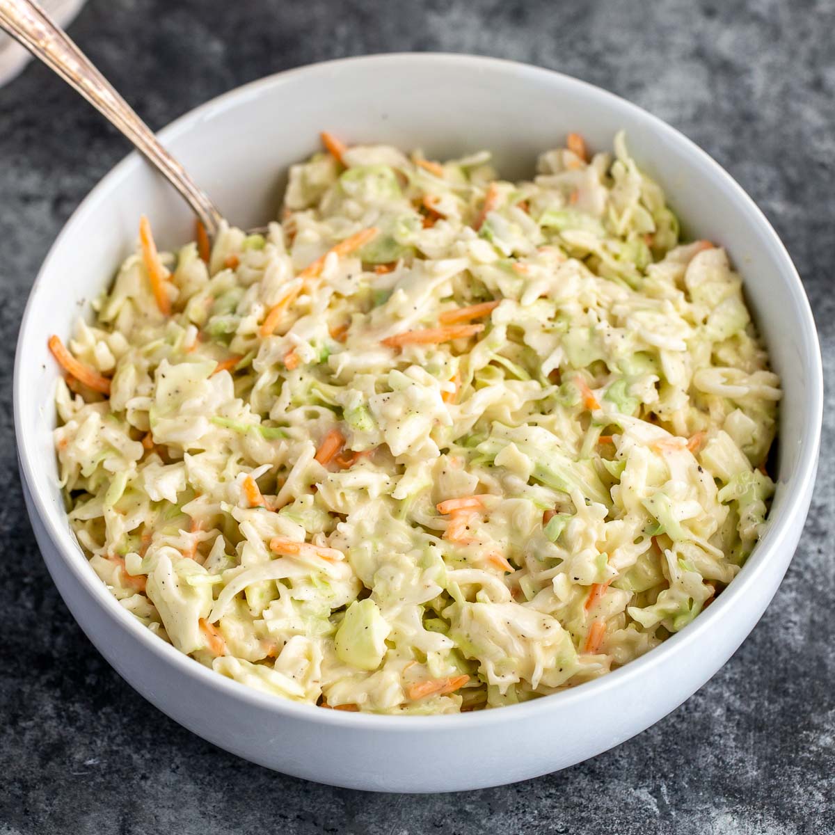 A large bowl filled with coleslaw that has been mixed with the dressing and ready to be served.